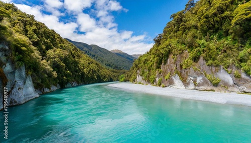 brilliant turquoise water caused by glacial flour flows through hokitika gorge surrounded by rocky limestone cliffs and lush vegetation on the south island of new zealand © Adrian