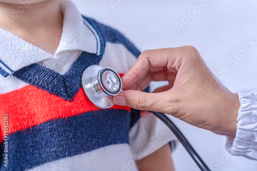 Close-up of a pediatrician using a stethoscope to listen to the heart rate and lungs of a young patient being treated for influenza. Epidemics in health care medical and health care concept.