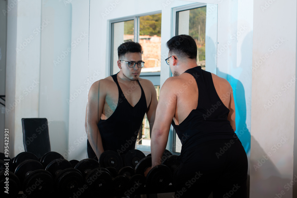 Obraz premium lifestyle: young adult looking in the mirror at the gym