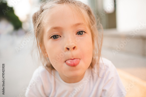 Close up portrait of baby girl 3-5 year old showing tongue outdoors