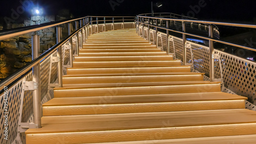 The staircase is illuminated at night. Evening lighting of pedestrian bridges. Lanterns at night. The light of the lanterns illuminates the stairs. Metal stairs for pedestrians to cross streets.
