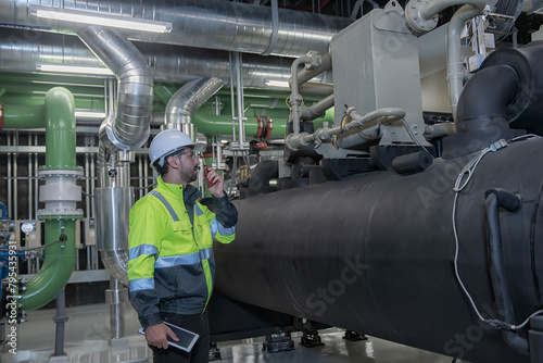 worker operating a machine. workers in factory. engineer work in Industrial  chiller  HVAC heating ventilation air conditioning system and pipping line of industrial construction at boiler pump room .