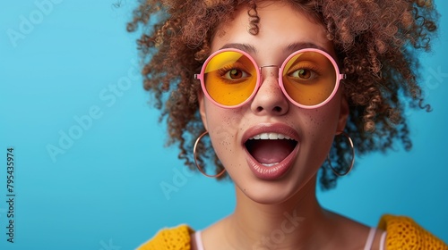 Influencer culture concept, young woman with surprised expression wearing sunglasses on blue background, beauty fashion lifestyle curly hair fun