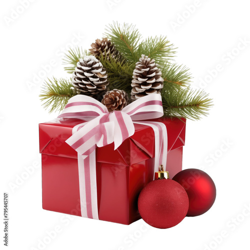 A red gift box with a white ribbon and a bow near a branch of a Christmas tree with toy balls and cones isolated on a white background