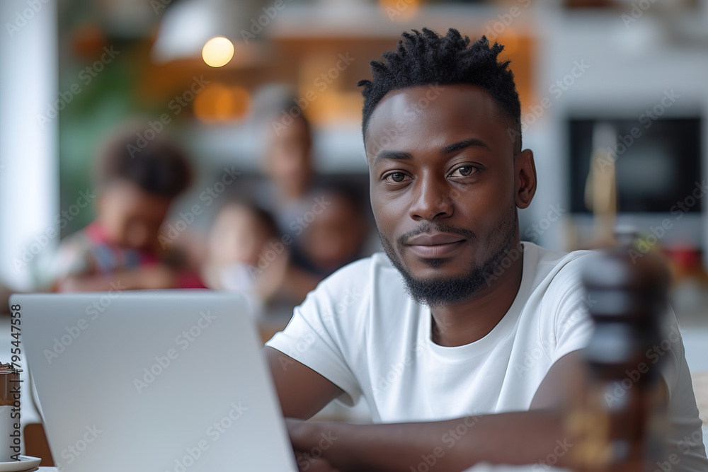 Young Black parent dad working from home office, African American father holding baby child daughter using laptop computer spending time with diverse multiracial family at home in the kitchen