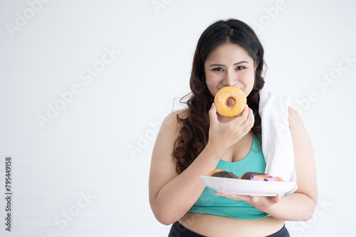 portrait chubby woman eats donuts with copy space	