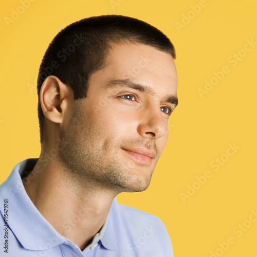 Square image - thinking young handsome man looking forward, isolated against orange yellow color background.