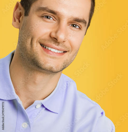 Portrait image of young happy smiling handsome attractive man fashion male model wear blue smart casual clothing, isolated against yellow orange color studio wall background.
