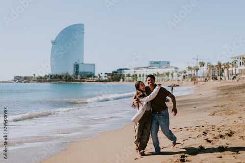Photography Joyful couple running hand in hand along a sunlit beach in Barcelona, Spain