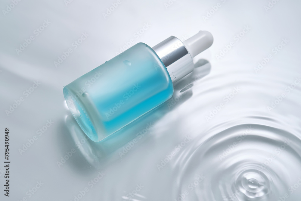Bottles of cosmetics with a dropper in water on a blue background. Bottles of cosmetics with a dropper in water on a blue background.