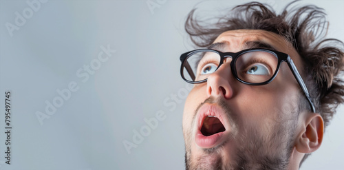 A man with glasses and a beard is looking at the camera with an open mouth. Concept of surprise or shock. a very surprised guy, close-up, lateral shot, THINKING, white background photo