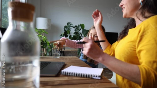 little girl playing while mother works remotely with her laptop Teleworking family.