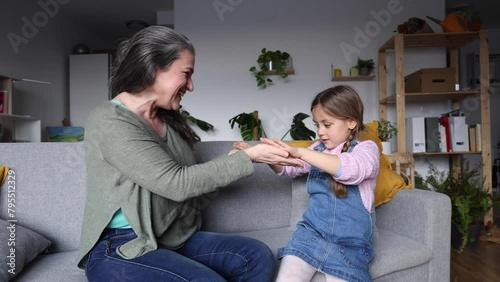 grandmother and granddaughter playing clapping on the living room sofa photo
