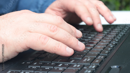  close-up of the hands of a man working on his laptop in the garden of his house  during the day