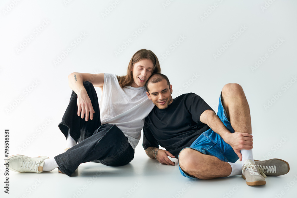 Obraz premium Two men sitting closely on the ground, sharing a loving moment.