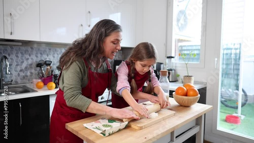 grandmother and granddaughter cook together. Grandma teaches how to roll the dough with a rolling pin