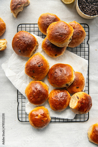 Freshly baked aromatic homemade chocolate and lemon brioche buns on cooling rack on linen tablecloth.