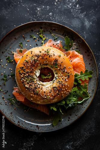 Top View Gourmet Bagel with Salmon. Top view of a bagel with smoked salmon and arugula on a dark plate, ideal for food-themed design. photo