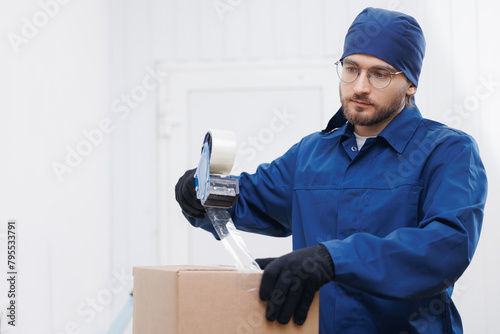 Warehouse industry, Packer working packs goods into box and seals them with tape on workplace