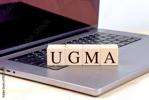 UGMA word on wooden block on a laptop , business concept photo