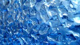   A tight shot of a blue glass wall filled with numerous ice cubes at its base