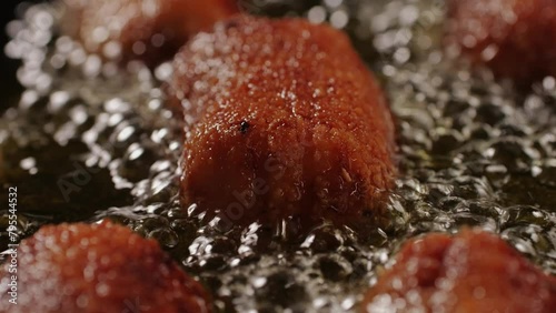 Portuguese Spanish croquettes boiling on black frying pan close-up macro. Breaded croquette of fish, potatoes and ham. Man cooking spanish food.  photo