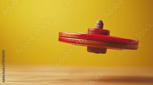  A red object with a protruding screw at its center on a weathered wood backdrop against a sunlit yellow background