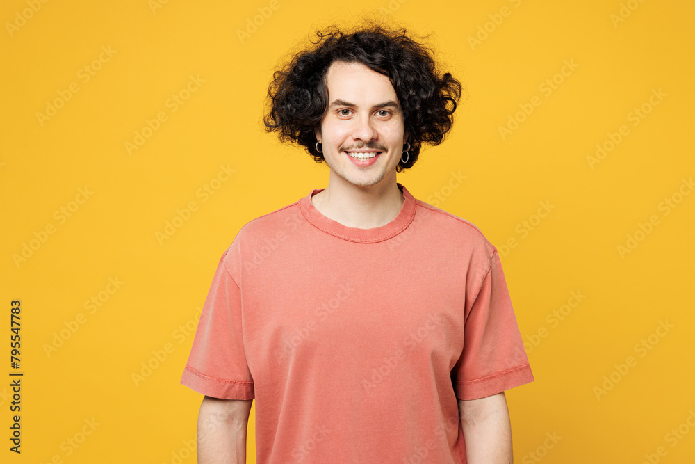 Young smiling happy satisfied cheerful man he wear pink t-shirt casual clothes look camera with toothy smile isolated on plain yellow orange wall color background studio portrait. Lifestyle concept. Young smiling happy satisfied cheerful man he wear pink t-shirt casual clothes look camera with toothy smile isolated on plain yellow orange wall color background studio portrait. Lifestyle concept.