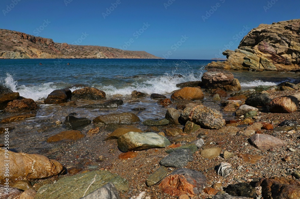 Colored stones on the shore of the Libyan Sea against the blue sky.