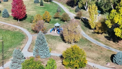 Aerial view of a wild meadow of unkept grass in a park next to playground equipment and paths in autumn when the tree leaves change colors.  photo