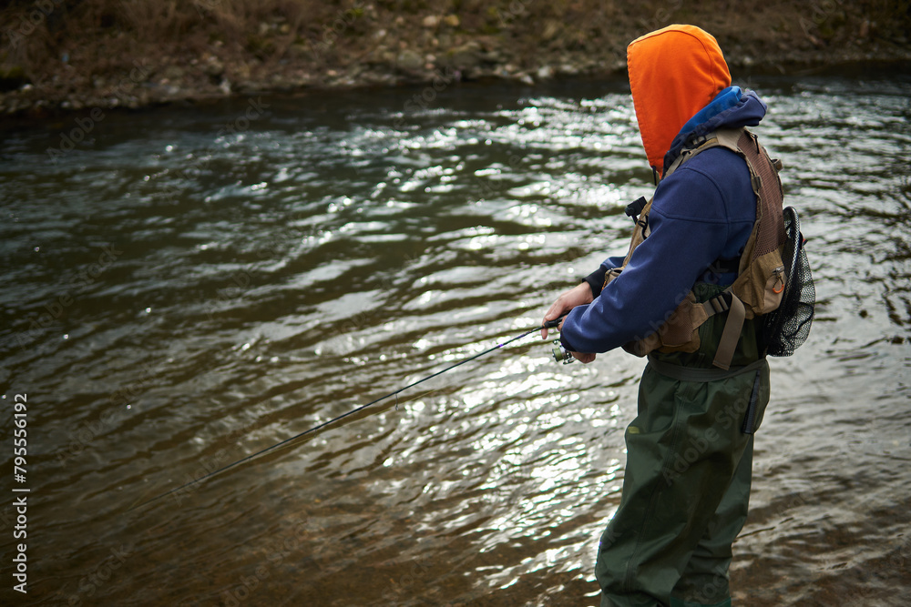 Fisherman fishing by the river in daytime with tackle bag and net Fisherman fishing by the river in daytime with tackle bag and net