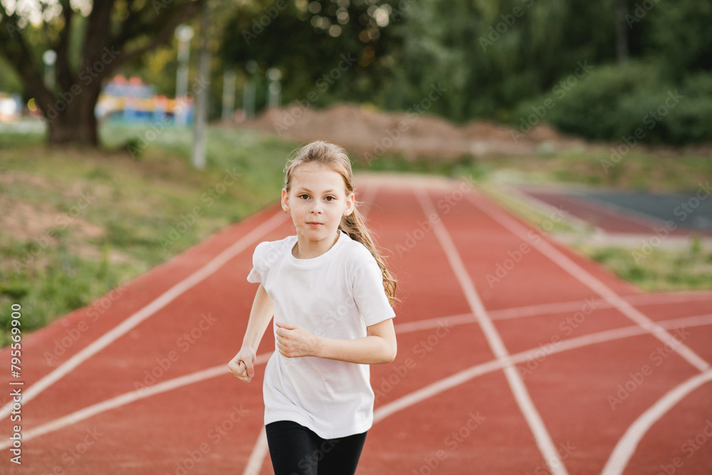 Obraz premium Focused child girl runner on a racing track. Confidence, empowerment, teamwork, accomplishment, and healthy physical habits.
