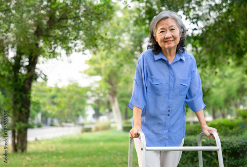 smiling senior woman walking with walker in park,concept of health insurance in elderly photo