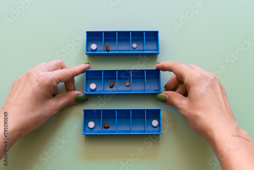 Organizing Medication with Weekly Pill Boxes on Green Background.