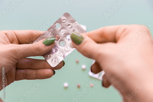 Hand holding blister pack with pills on green background. photo