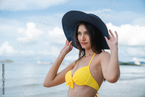 Woman in a bikini relishing her time on a tropical beach. She relaxes on the sandy shore, embodying the essence of summer vacation.