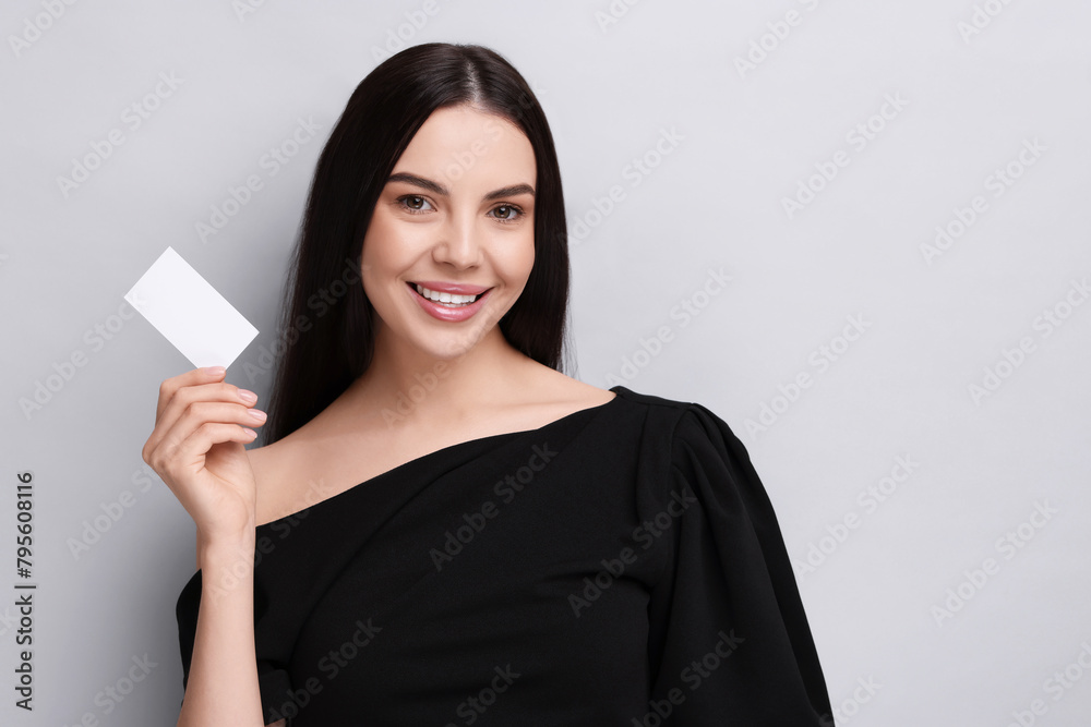 Happy woman holding blank business card on light grey background. Space for text Happy woman holding blank business card on light grey background. Space for text