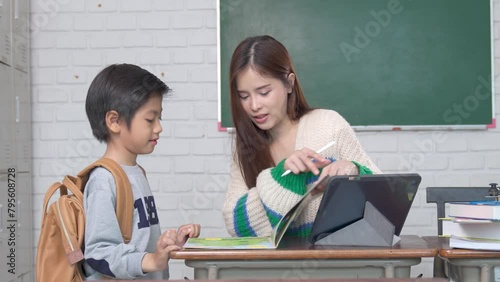 Smiling Asian female lecturer helping children student during classroom. Education knowledge, successful teamwork concept.