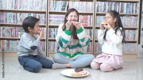 Asian teacher and children student taking break having fun while eating donuts.