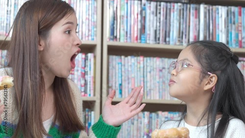 Asian teacher and children student taking break having fun while eating donuts.