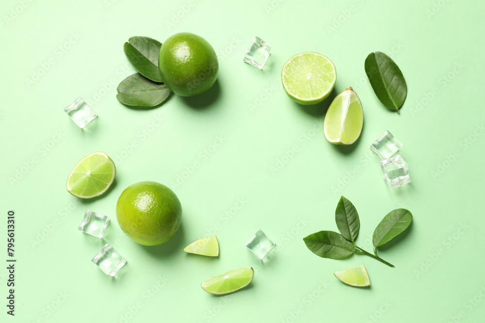 Frame made of ripe limes with leaves and ice cubes on light green background, flat lay Frame made of ripe limes with leaves and ice cubes on light green background, flat lay