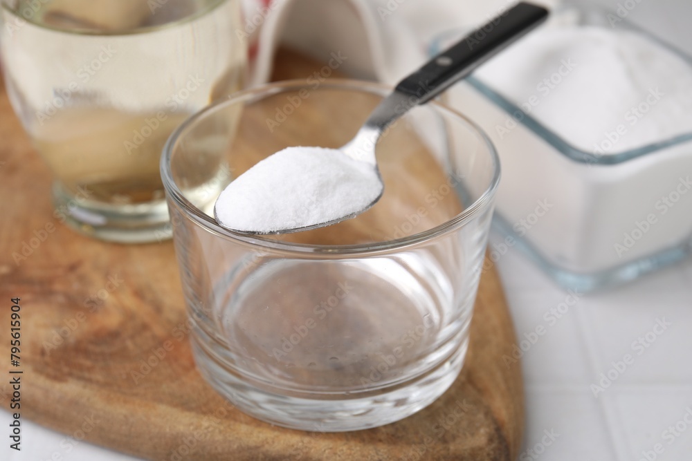 Baking soda in spoon, glass bowl and vinegar on white table, closeup Baking soda in spoon, glass bowl and vinegar on white table, closeup