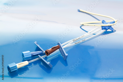 Triple lumen short-term central venous catheter with three infusion channels reflected on blue background 