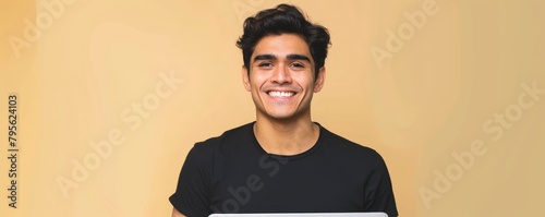 A portrait of the young man using computer laptop and smiling for the camera with one color background..