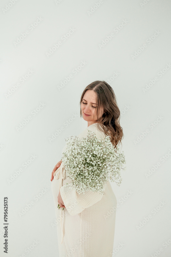 Beautiful young pregnant woman with on white background. Stylish pregnant woman in beige dress. Motherhood. Mother's Day. Beautiful young pregnant woman with on white background. Stylish pregnant woman in beige dress. Motherhood. Mother's Day.