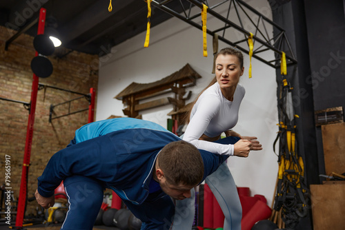 Woman training with man practicing martial arts at gym