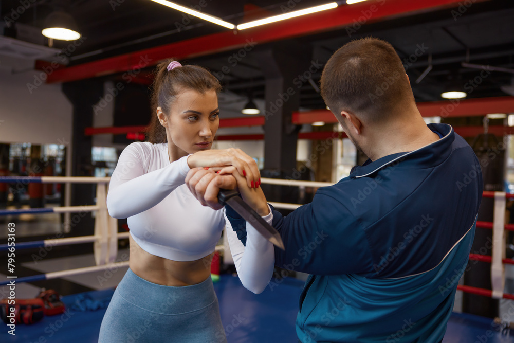 Naklejka premium Woman exercising with martial arts trainer practicing self-defense from knife