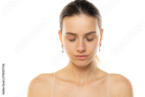 Portrait of a young serious teenage girl without makeup and closed eyes on a white background