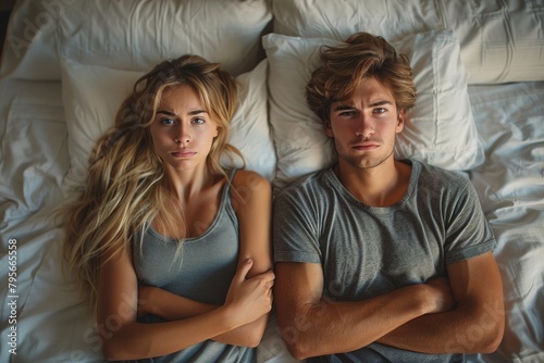 A young couple lies in bed side by side, displaying expressions of concern, tension, and unsaid thoughts