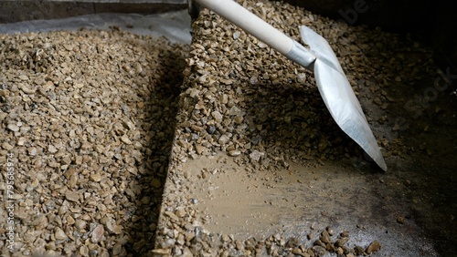 A pile of gray rubble with a shovel and small stones in the room. Crushed stone with a shovel, close-up.